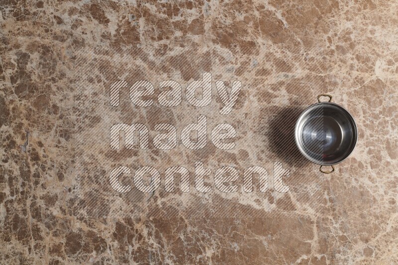 A small copper pot on beige marble background