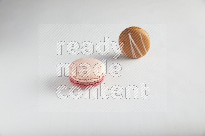 45º Shot of of two assorted Brown Irish Cream, and Pink Litchi Raspberry macarons on white background