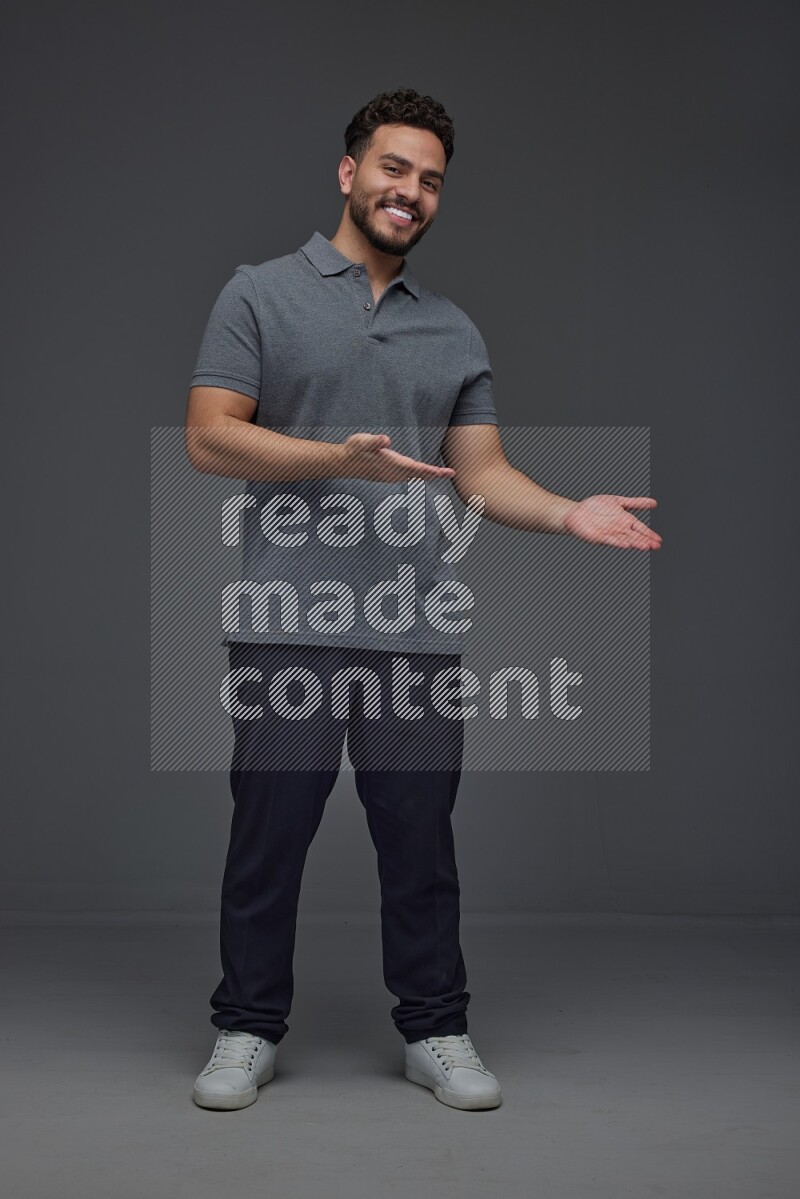 A man wearing casual standing and making multi hand gestures eye level on a gray background