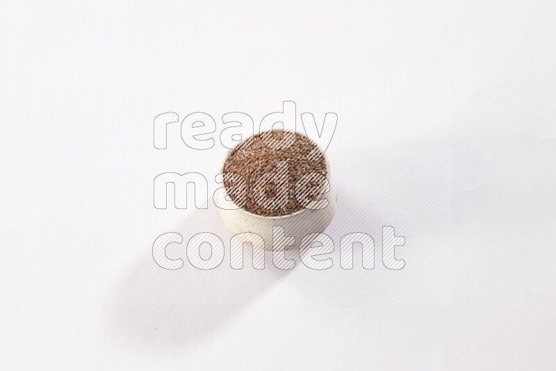 A pottery beige bowl full of flax seeds on a white flooring