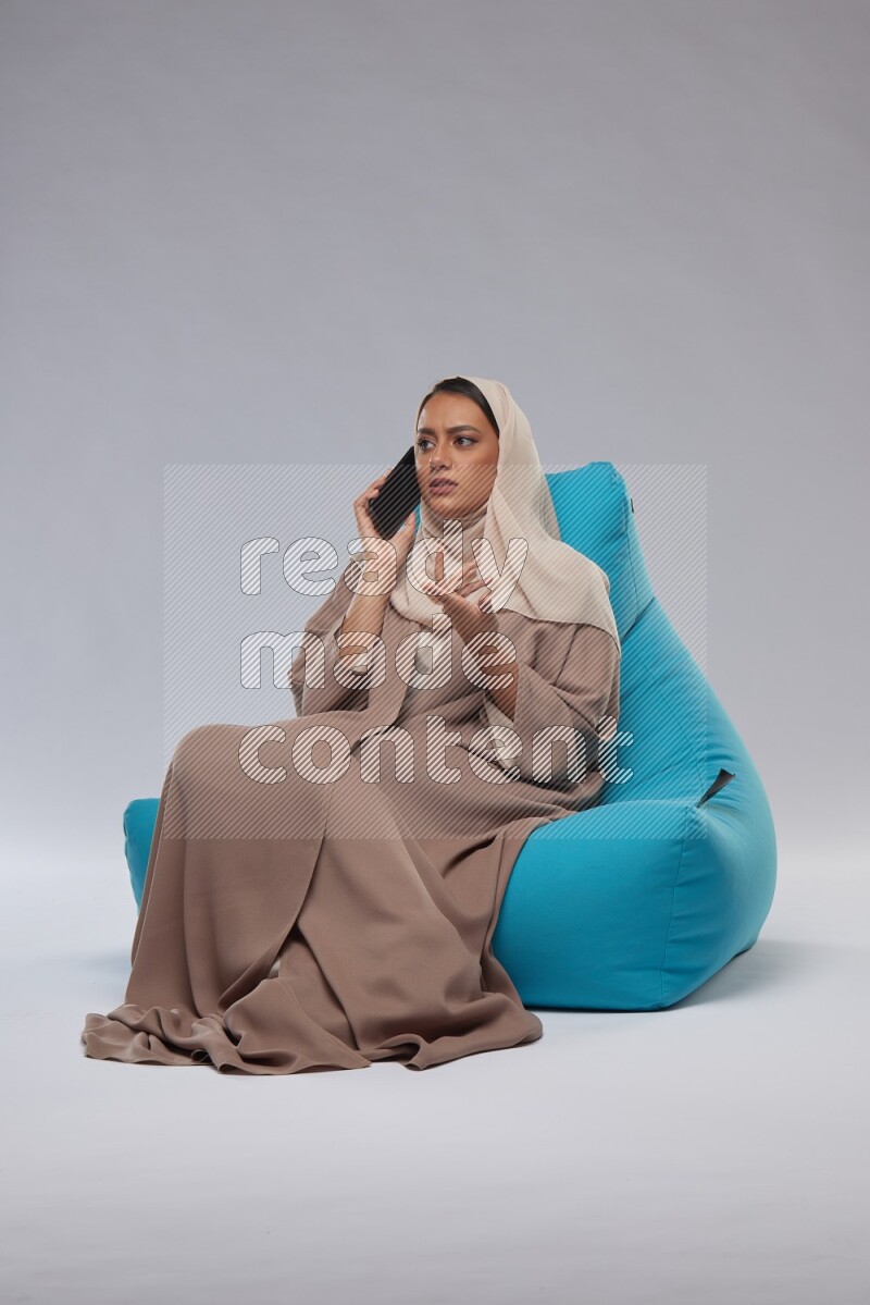 A Saudi woman sitting on a blue beanbag and working on laptop
