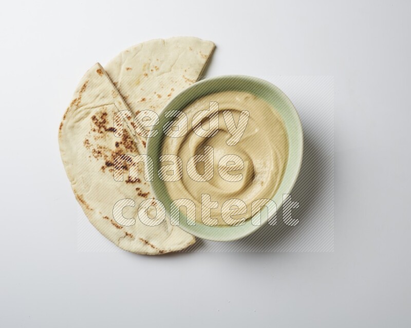 plain Hummus in a green plate on a white background