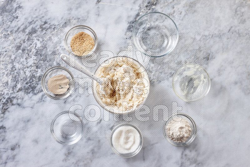 Kahk step by step with its ingredients ghee, sugar, flour, sesame, yeast, water and kahk flavor on grey marble background
