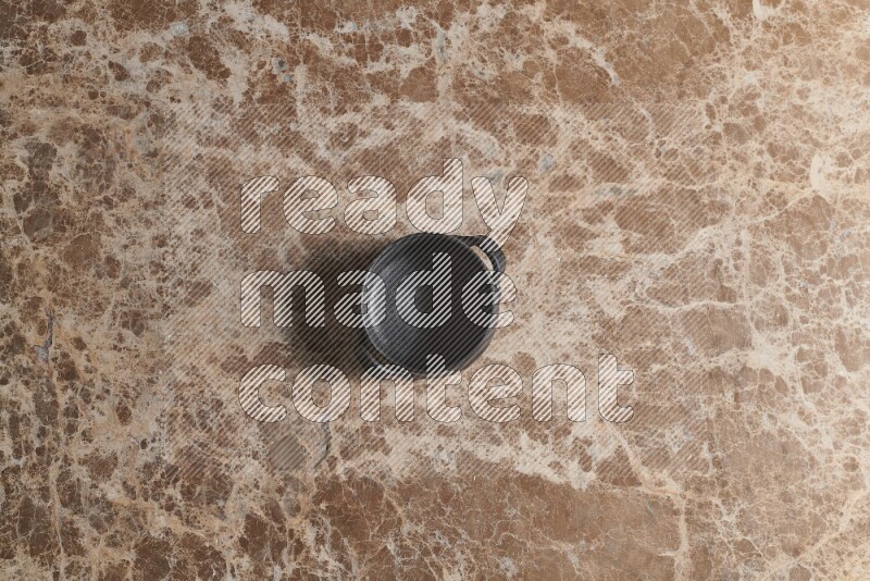 A black pottery bowl on beige marble background