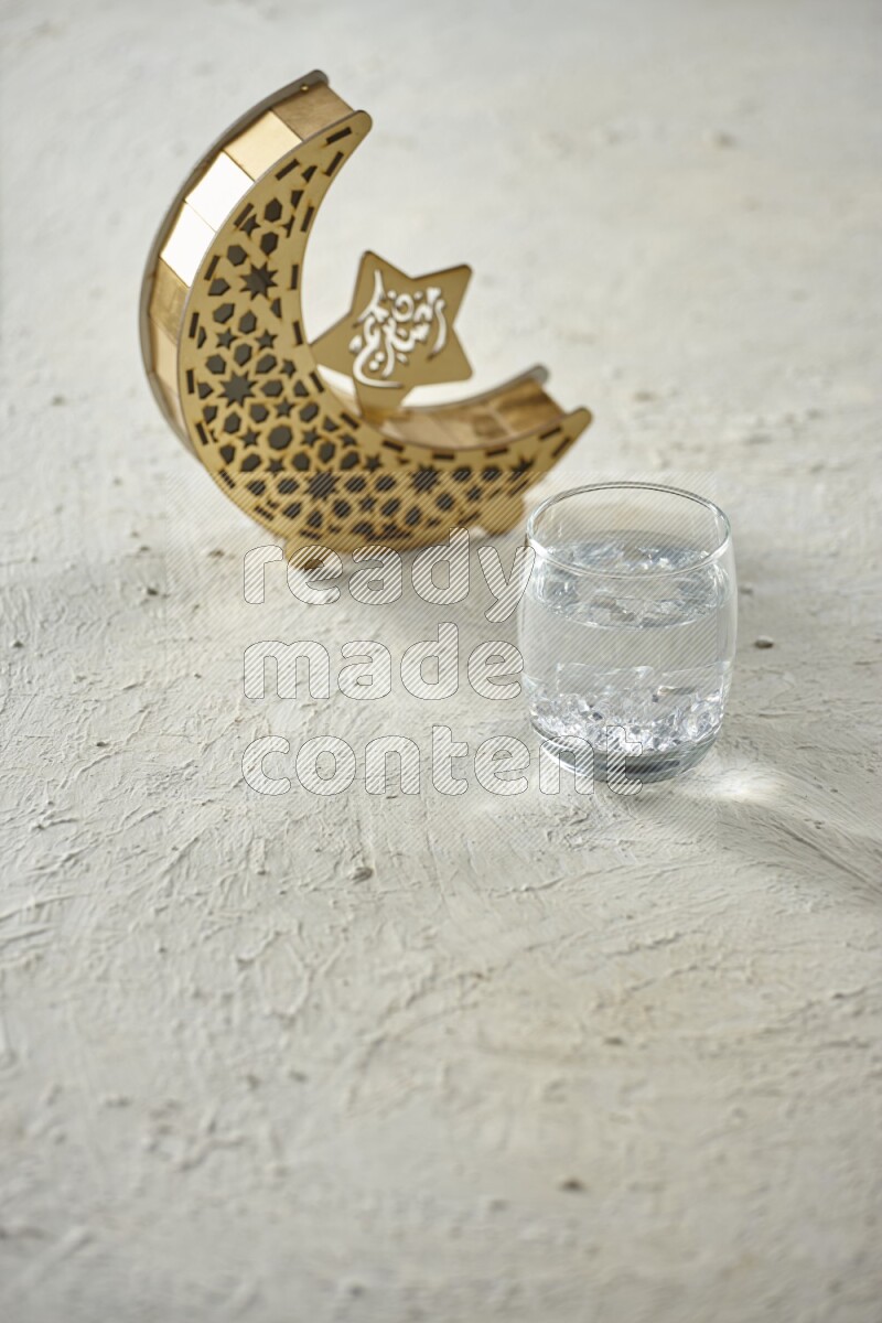 A wooden golden crescent lantern with different drinks, dates, nuts, prayer beads and quran on white background