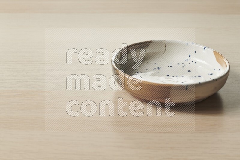 A multicolored pottery bowl on light wooden background