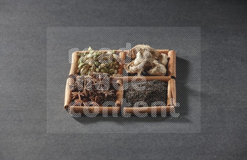 4 squares of cinnamon sticks full of tea, star anise, dried ginger and cardamom on black flooring