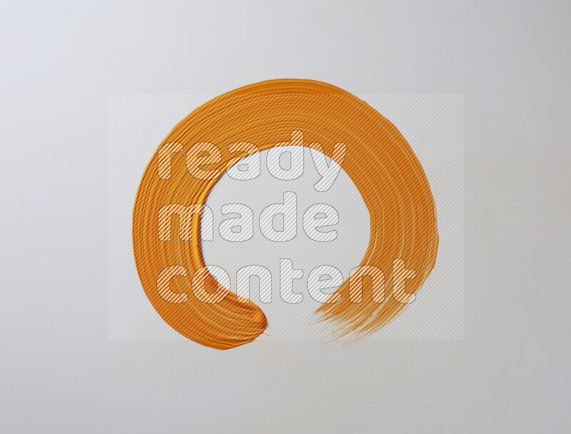 An orange circular painting brush stroke on white background