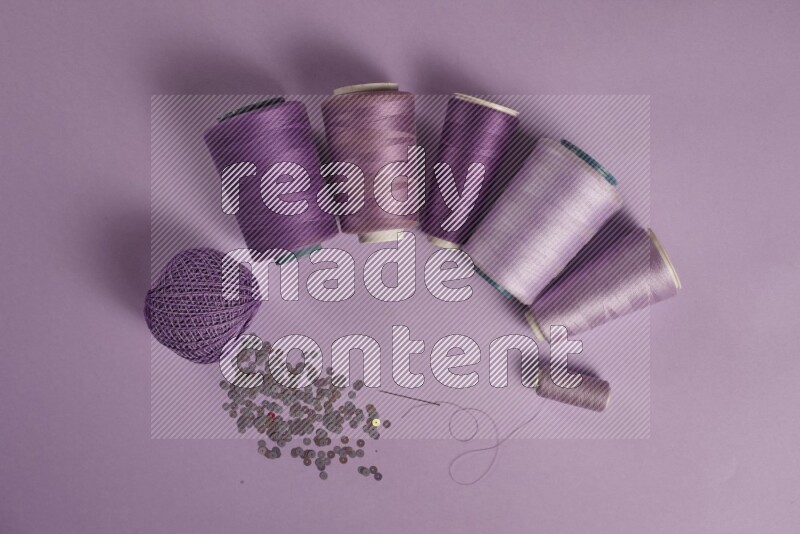 A purple collection of sewing and tailoring tools arranged on a purple background