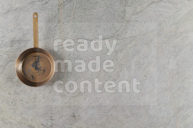 A small copper pan on grey marble background