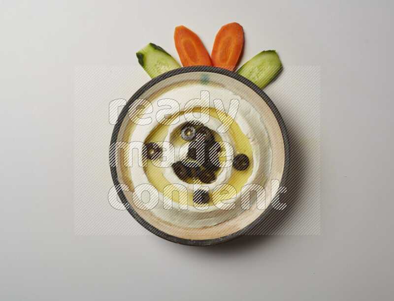 Lebnah garnished with sliced olives in a pottery plate on a white background