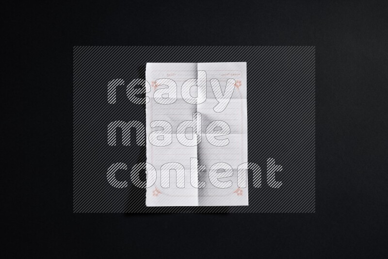 Folded notebook sheet on black background