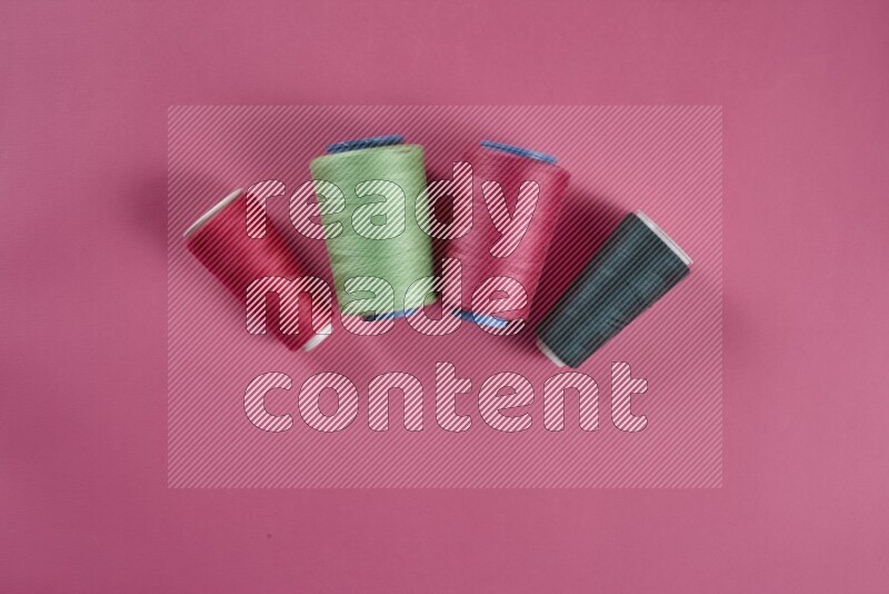 A green and pink collection of sewing and tailoring tools arranged on a pink background
