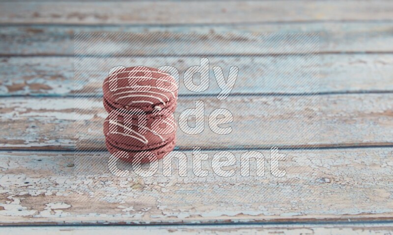 45º Shot of two Red Poppy Flower macarons on light blue wooden background