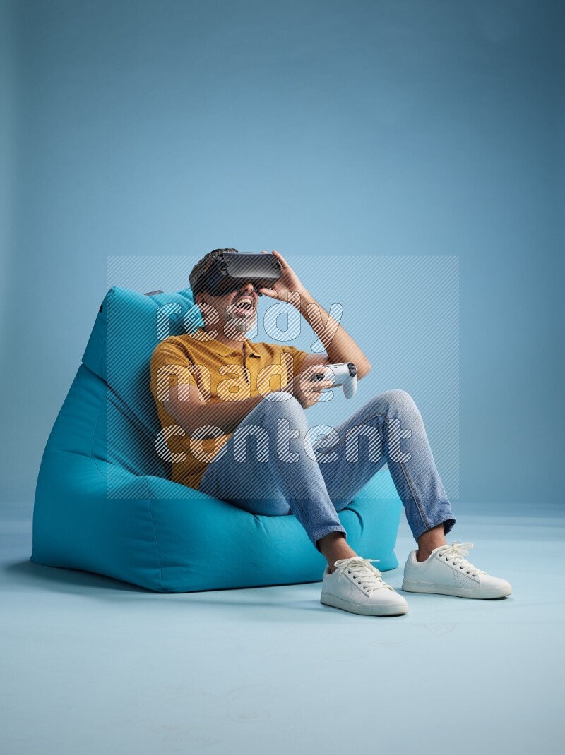 A man sitting on a blue beanbag and gaming with VR