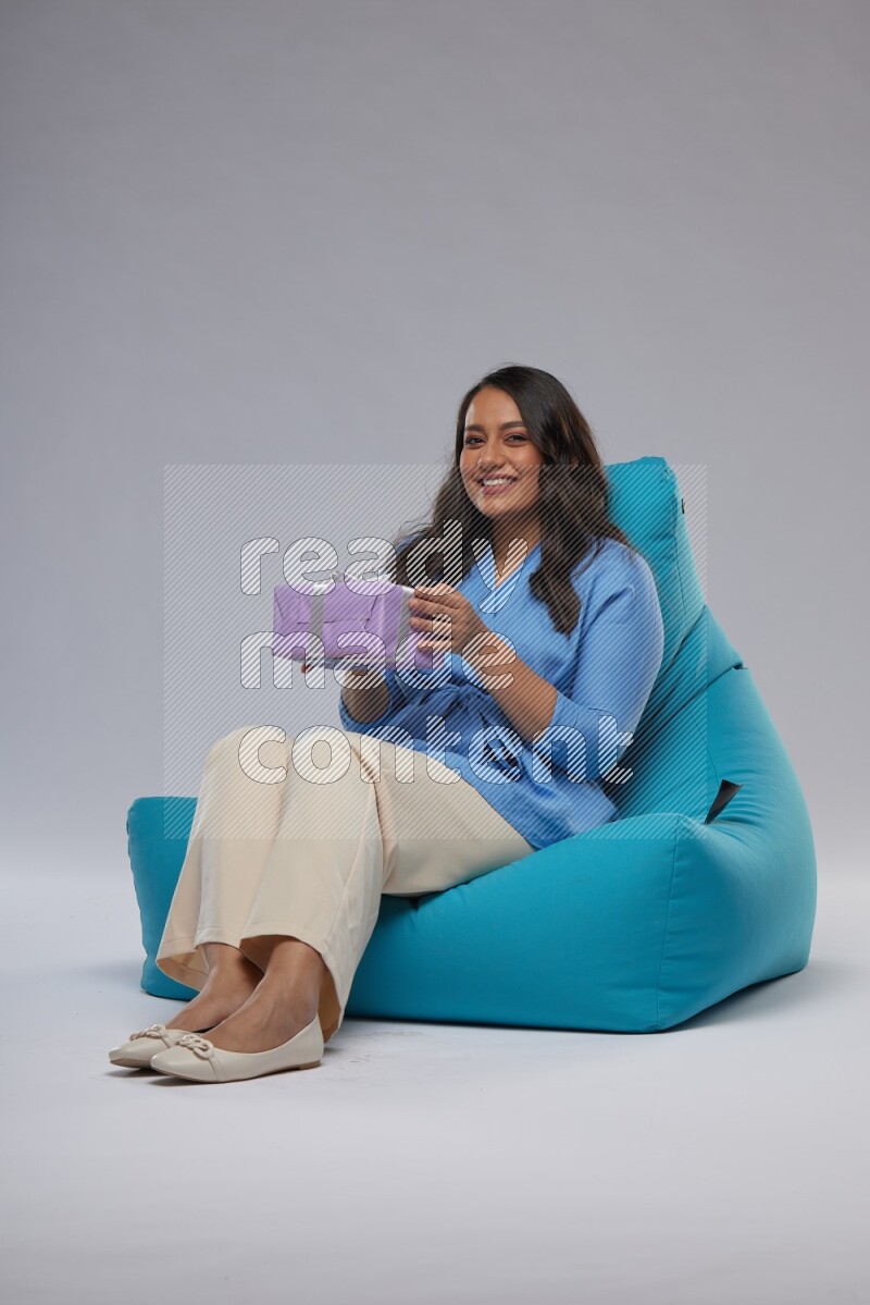 A woman sitting on a blue beanbag and holding a gift