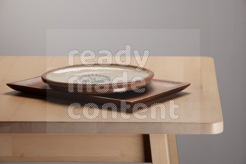 multicolored plate on a rectangular wooden tray on the edge of wooden table