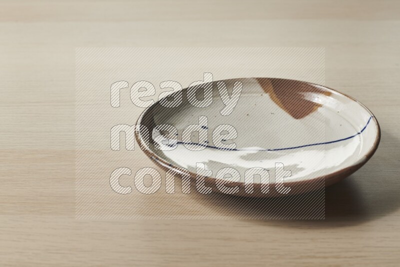 A multicolored pottery plate on light wooden background
