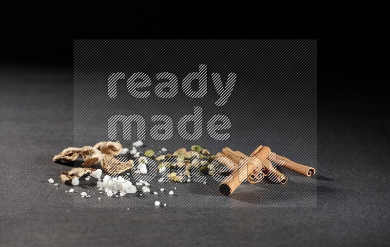 الزنجبيل والملح والهيل وأعواد القرفة على خلفية سوداء