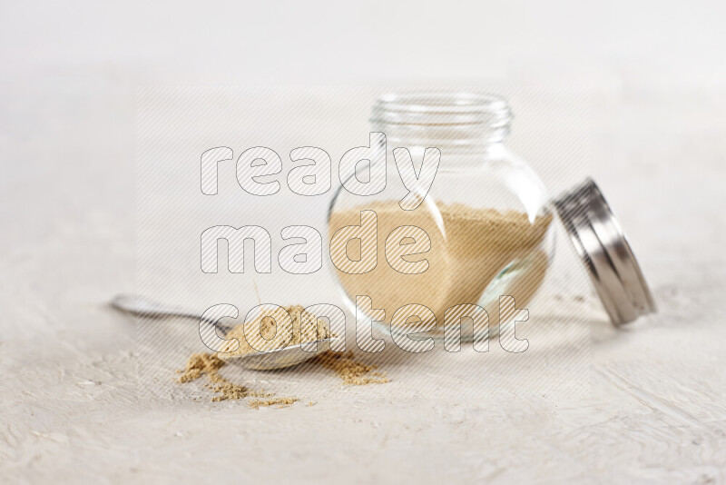 A glass jar full of ground ginger powder on white background