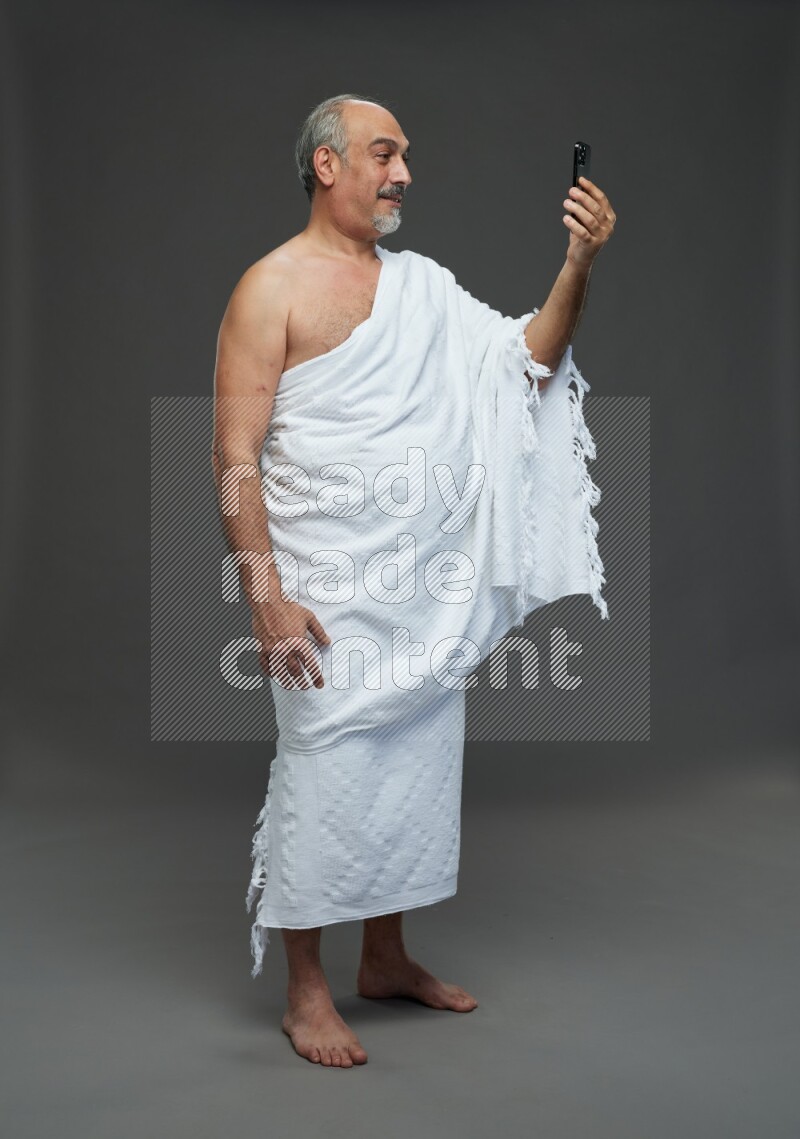 A man wearing Ehram Standing taking selfie on gray background