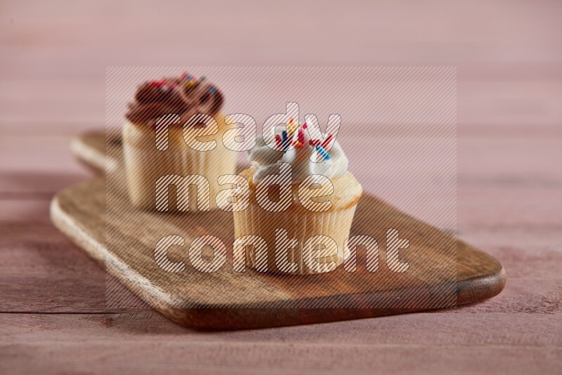Vanilla mini cupcake topped with cream on a wooden board
