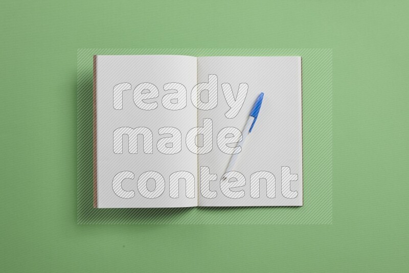 A blank open notebook with different school supplies on green background