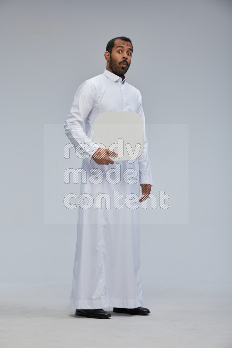 Saudi man wearing Thob standing holding social media sign on Gray background