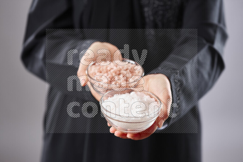 Woman in abaya holding different kinds of spices in different positions