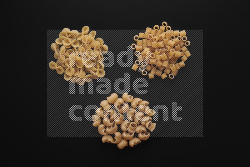 Different pasta types in bunches on black background