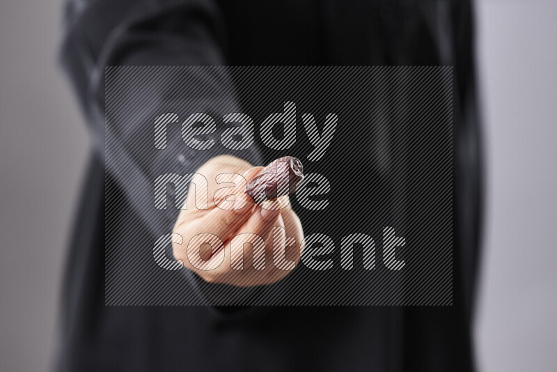 امرأة ترتدي عباءة تحمل أنواع مختلفة من التمر في أوضاع متعددة