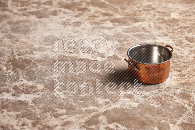 A small copper pot on beige marble background