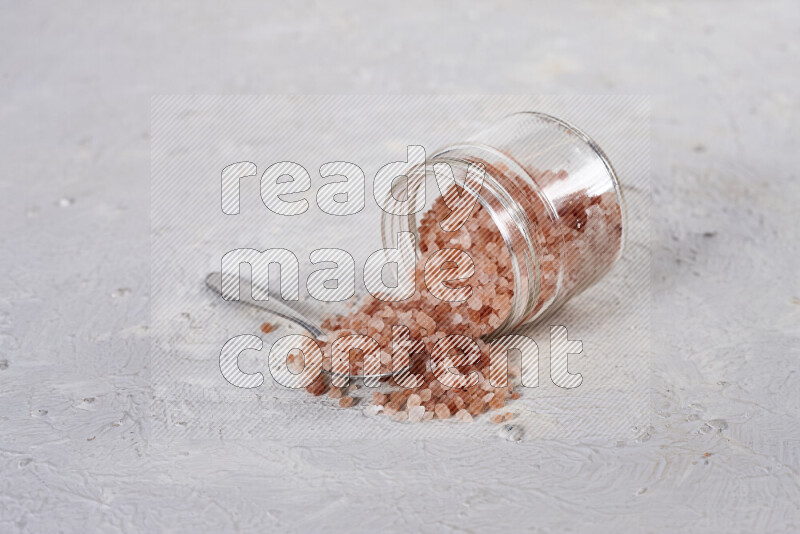 A glass jar full of coarse himalayan salt crystals on white background