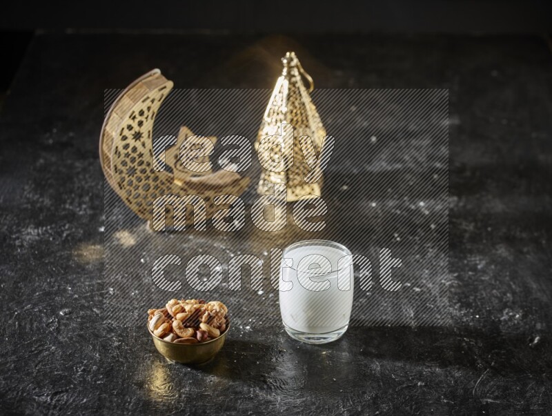 Nuts in a metal bowl with sobia beside golden lanterns in a dark setup