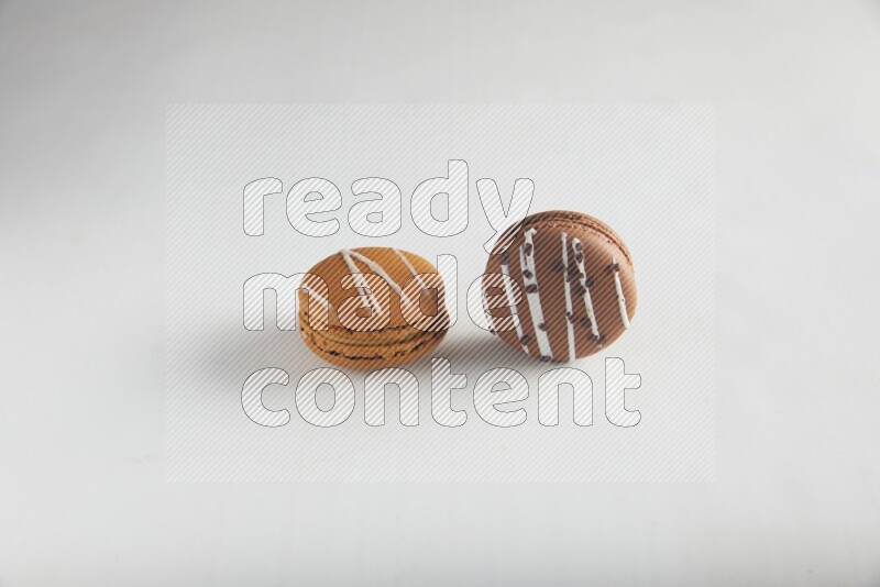 45º Shot of of two assorted Brown Irish Cream, and Brown white Chocolate Caramel macarons on white background