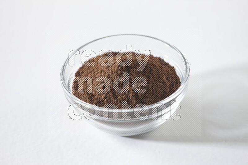 A glass bowl full of cloves powder on white flooring