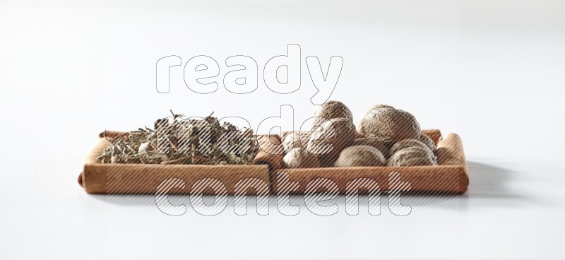 2 squares of cinnamon sticks full of dried basil and nutmegs on white flooring