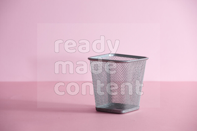 Pens, pencils and other different school supplies in a metal pen holder on rose background