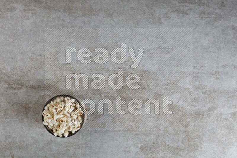 popcorn in multi-colored pottery bowl on a grey textured countertop