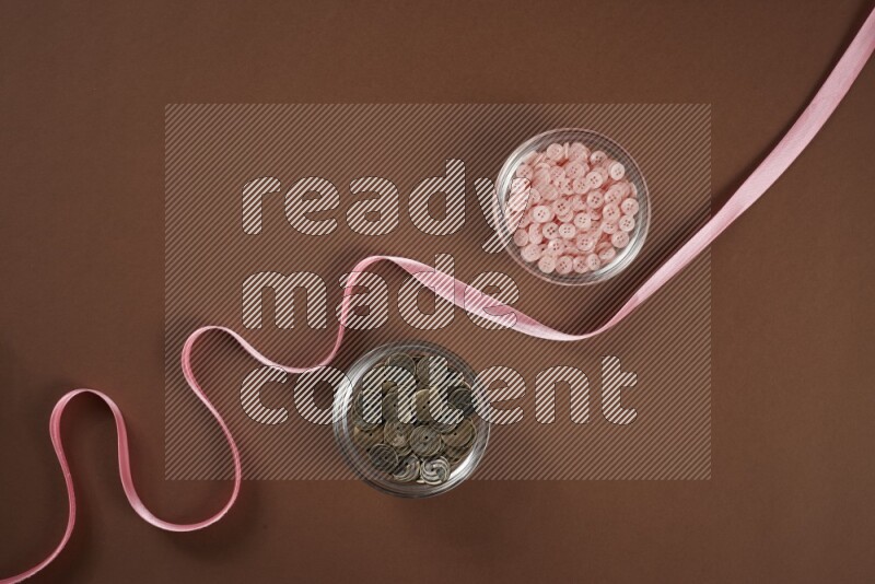 A pink collection of sewing and tailoring tools arranged on a brown background