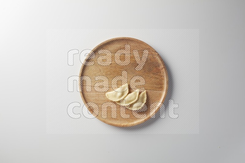 Three Sambosas on a wooden round plate on a white background