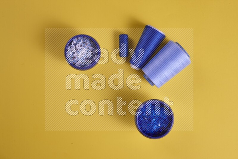 مجموعة من أدوات الخياطة والتفصيل زرقاء اللون على خلفية صفراء