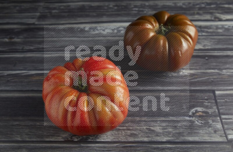 45 degree two heirloom tomato on a textured grey wooden background