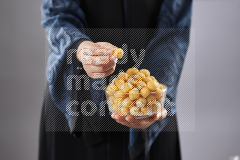 Woman in abaya holding different kinds of snacks in different positions