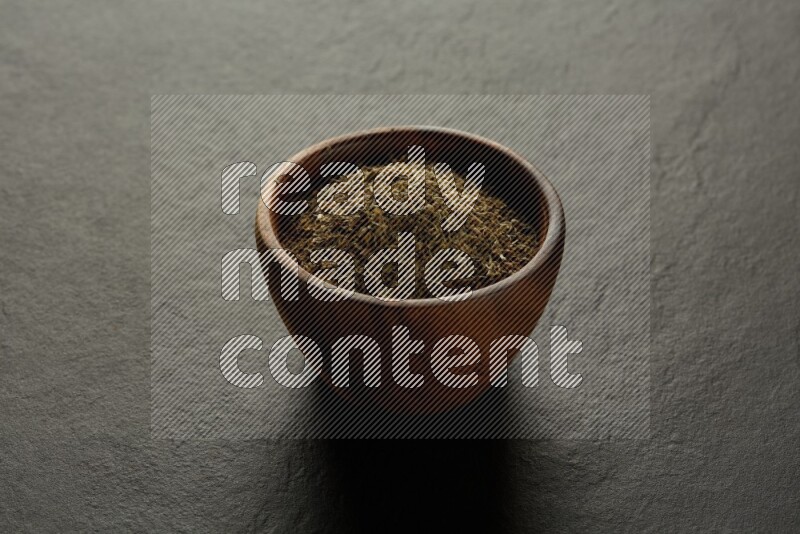 wooden round sauce bowl filled with herbs on grey textured countertop