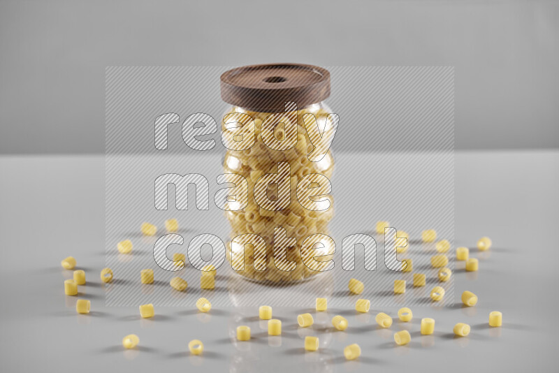 Raw pasta in a glass jar on light grey background
