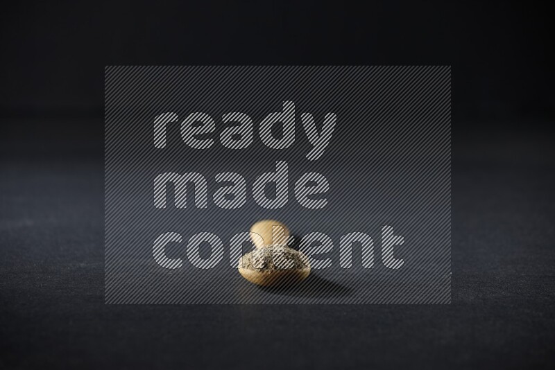 ملعقة خشبية ممتلئة ببودرة الهيل على خلفية سوداء