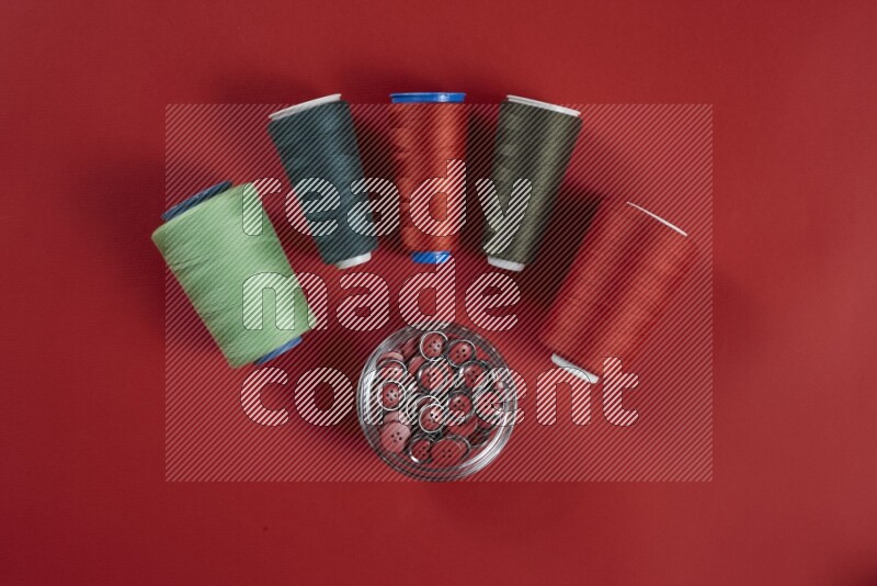 A green and red collection of sewing and tailoring tools arranged on a red background