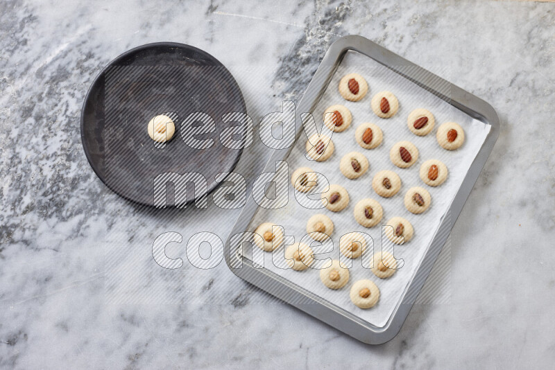 Ghoriba step by step with its ingredient, flour, powdered sugar, ghee and nuts on grey marble background