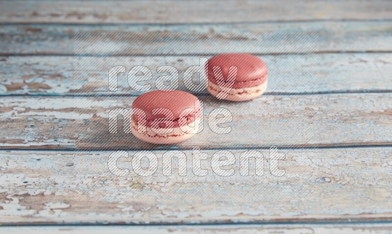 45º Shot of two Pink Litchi Raspberry macarons on light blue wooden background